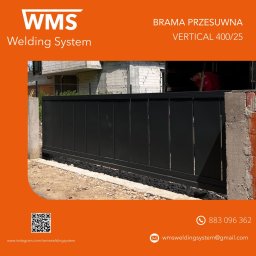 WMS Group Poland Sp. z o.o. - Czarna, przesuwna brama wjazdowa VERTICAL 400/25 z widocznym fragmentem montażu i pracownikiem w tle, wykonana przez WMS Welding System.