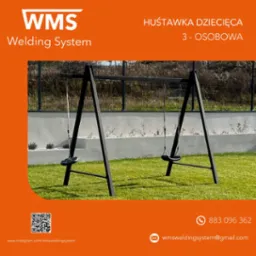 Metalowa konstrukcja huśtawki dla dzieci, trzyosobowa, na tle zielonego trawnika i ogrodzenia. Widoczny branding firmy WMS Welding System.