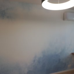 Oleg FENYAK - Ściana w pokoju z efektem malarskim przypominającym chmury, oświetlona okrągłą lampą sufitową i z zamontowanym klimatyzatorem.