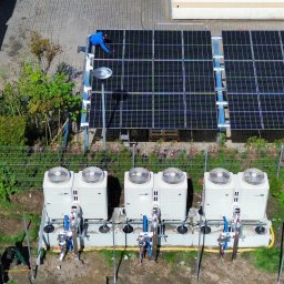 PRO-BUD DANIEL BOŁOTOW - Montaż instalacji z panelami słonecznymi i pompami ciepła. Widok z góry ukazuje prace instalacyjne, panele oraz urządzenia w otoczeniu zieleni.