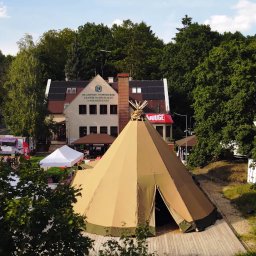 KPCEEiS GRZEGORZ WĄS - Widok z góry na duży namiot tipi przed budynkiem Kujawsko-Pomorskiego Centrum Edukacji Ekologicznej, w tle las i food truck.
