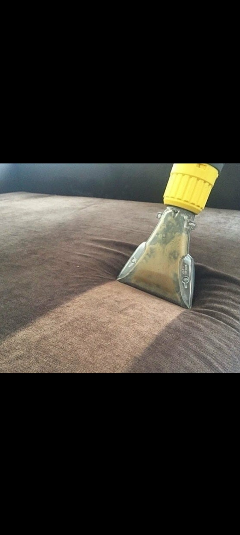 Dysza odkurzacza piorącego w trakcie czyszczenia brązowej kanapy, widoczny efekt czyszczenia na powierzchni materiału.