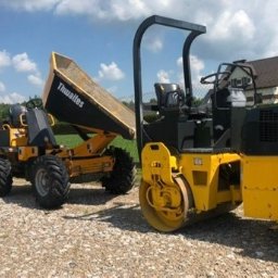 C-TECH SPÓŁKA Z OGRANICZONĄ ODPOWIEDZIALNOŚCIĄ - Żółty walec drogowy oraz wywrotki Thwaites na żwirowym placu, w tle dom jednorodzinny i ogrodzenie z siatki.