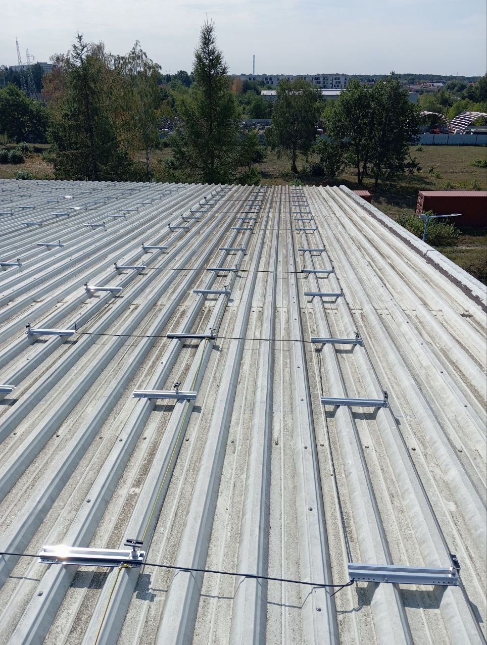 Montaż konstrukcji wsporczej pod panele fotowoltaiczne na blaszanym dachu w Toruniu, widok z góry na przygotowany do instalacji system mocowań.