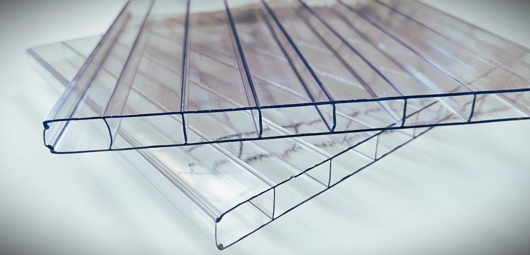 Przezroczyste płyty poliwęglanowe komorowe ułożone warstwowo, widoczne wewnętrzne struktury i przekrój poprzeczny.