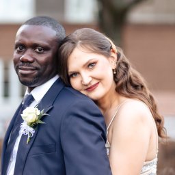 Okiem Alicji - Uśmiechnięta para: mężczyzna w granatowym garniturze z butonierką z białej róży i kobieta w sukni z cekinami, obejmująca go czule.