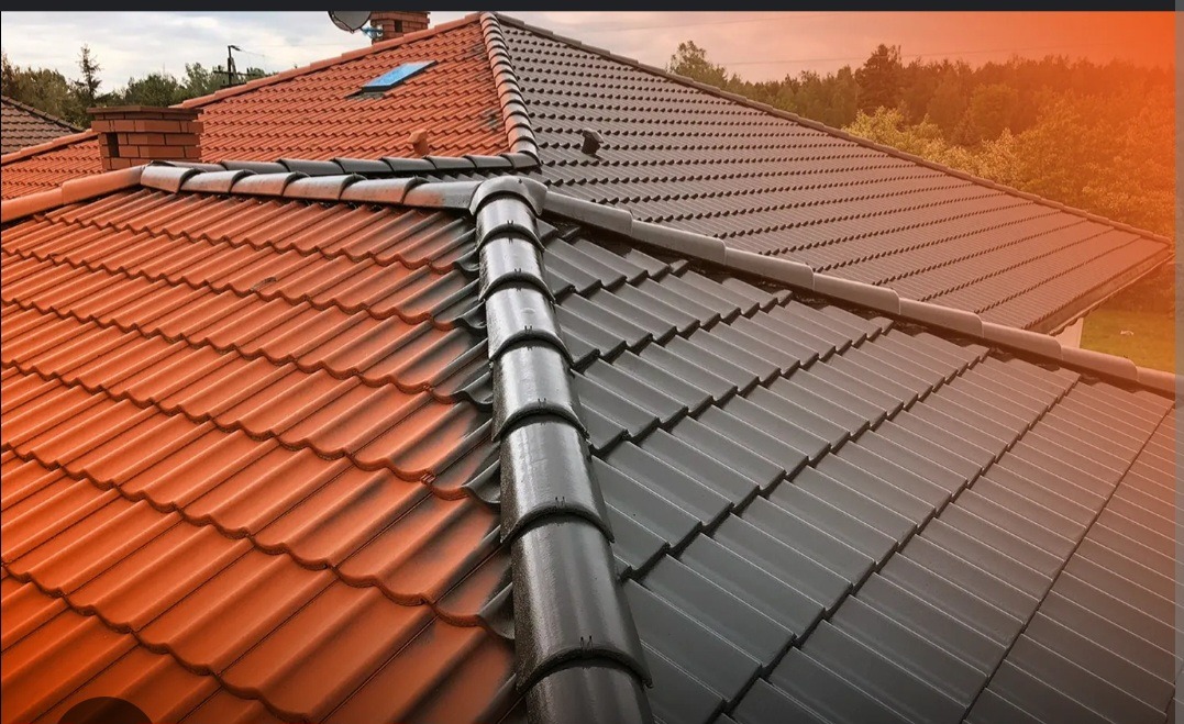 Częściowo pomalowany dach z dachówki ceramicznej, widoczna różnica kolorów między starą czerwoną a nową szarą powłoką, mokre elementy po czyszczeniu lub deszczu.