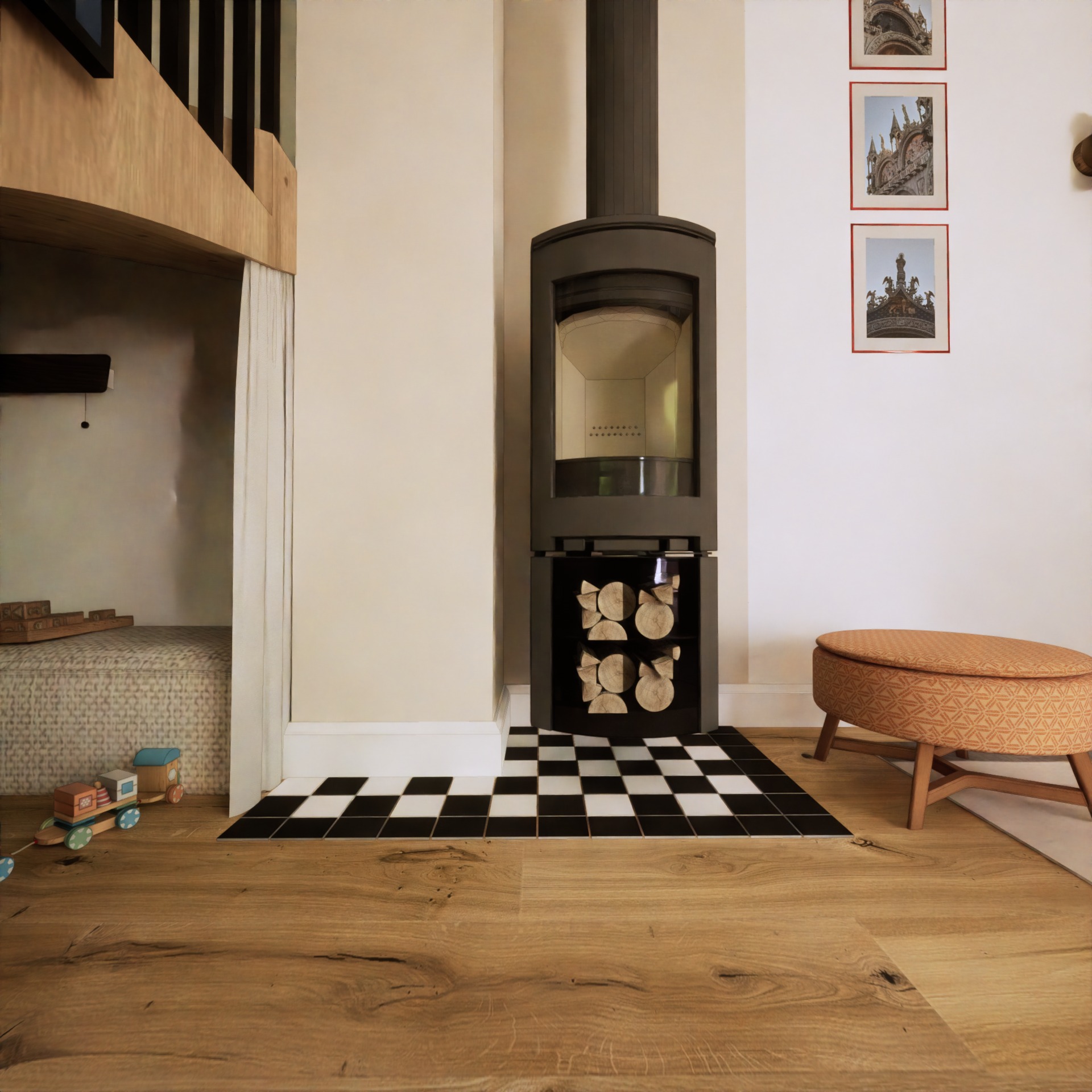 Wnętrze pokoju z kominkiem, drewnianą podłogą, czarno-białą szachownicą z płytek, pufą w geometryczny wzór, zabawkami dla dzieci i schodami z drewnianą barierką prowadzącymi na antresolę z zasłoną.