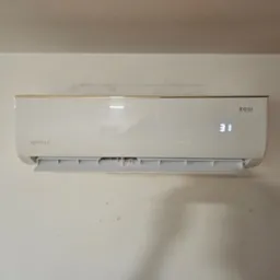 Biały klimatyzator Rotenso z wyświetlaczem temperatury (31 stopni Celsjusza) zamontowany na jasnej ścianie. Widoczne detale obudowy i żaluzje wylotu powietrza.