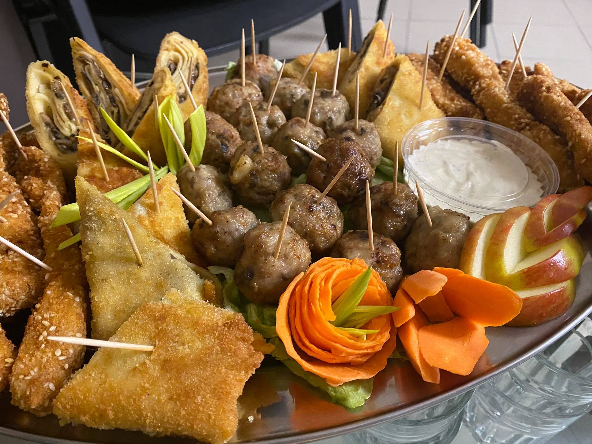 Elegancko ułożony srebrny półmisek z różnorodnymi przekąskami cateringowymi: mini-kotleciki na szpilkach, smażone pierożki z farszem grzybowym, chrupiące kąski w sezamowej panierce, dekoracje...