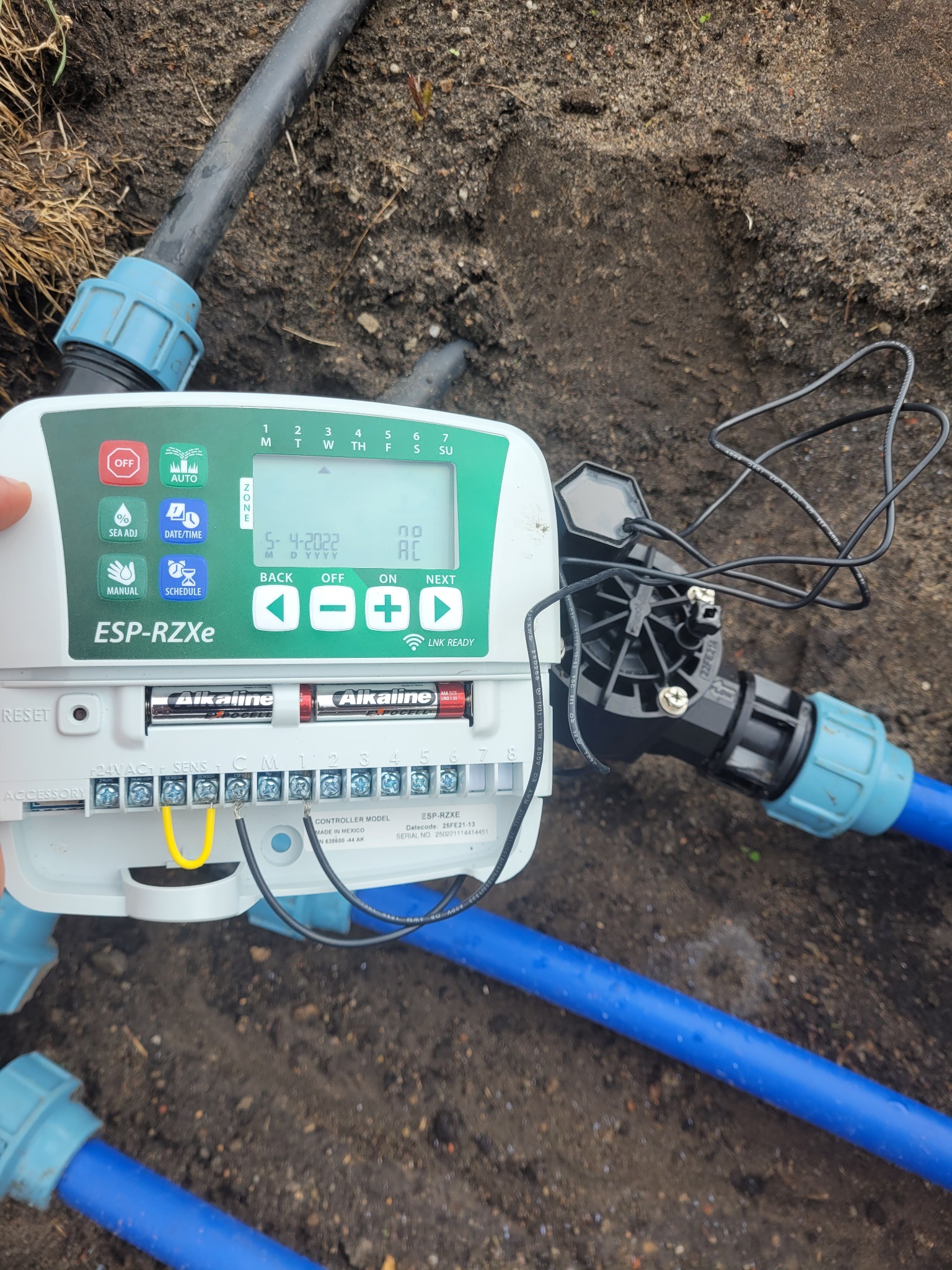 Szczegółowe ujęcie panelu sterującego systemem nawadniania ESP-RZXe z podłączonymi przewodami i rurami w ziemi, instalacja w Szczecinie.