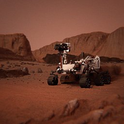 Paranoia Studio - Model łazika marsjańskiego na tle marsjańskiego krajobrazu z czerwonym piaskiem i skałami. Złożona konstrukcja z kamerami i kołami, symulacja eksploracji kosmosu.
