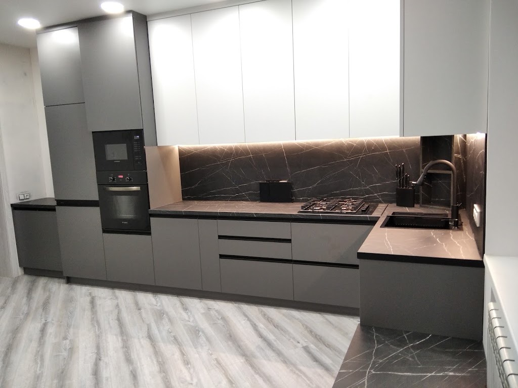 Nowoczesna kuchnia z szarymi szafkami dolnymi i białymi górnymi, czarny blat imitujący marmur, podświetlenie LED i szara podłoga imitująca drewno.