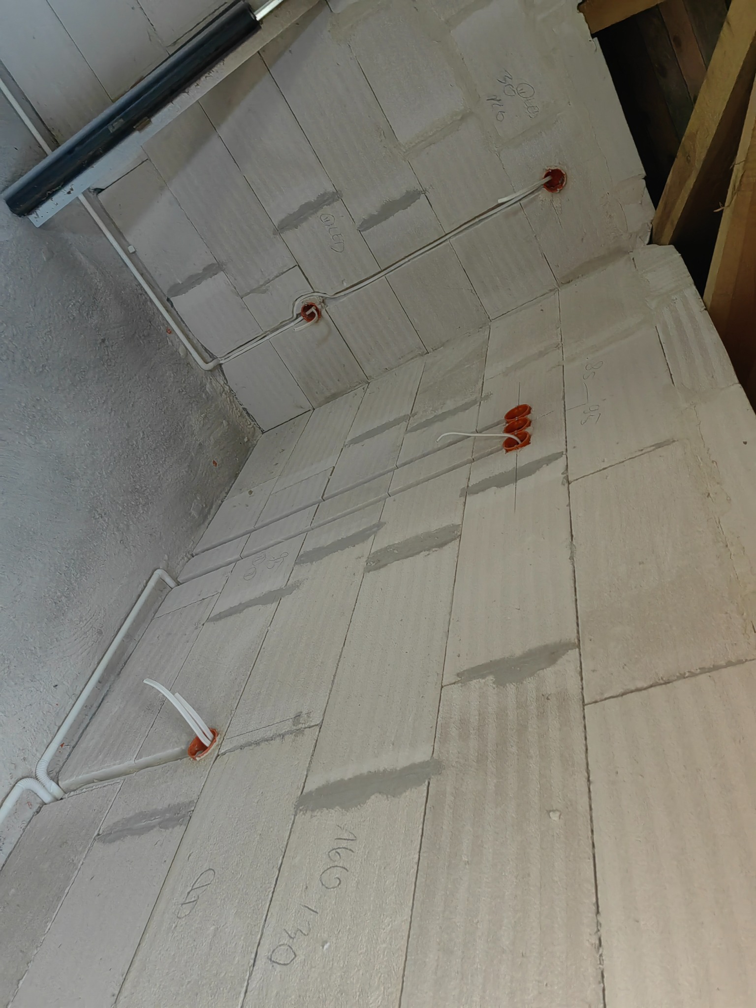 Wewnętrzne ściany z betonu komórkowego z widocznymi przewodami elektrycznymi w peszlach i puszkach instalacyjnych, przygotowane do dalszych prac wykończeniowych.