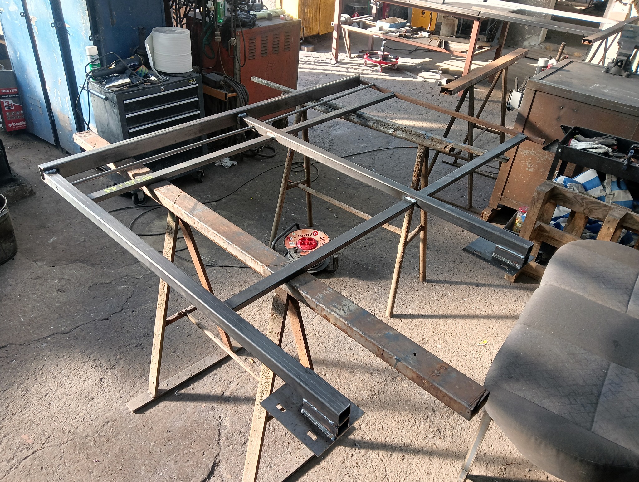 W trakcie tworzenia metalowej konstrukcji w Opolu. Spawane profile stalowe ułożone na kozłach. Widoczne narzędzia i elementy warsztatu.