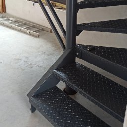 VIKTET-SPAV Viktor Slobodianiuk - Ciemne, spiralne schody metalowe z blachy ryflowanej w surowym wnętrzu. W tle okno i drabina. Ujęcie z dołu, ukazujące konstrukcję i fakturę stopni.