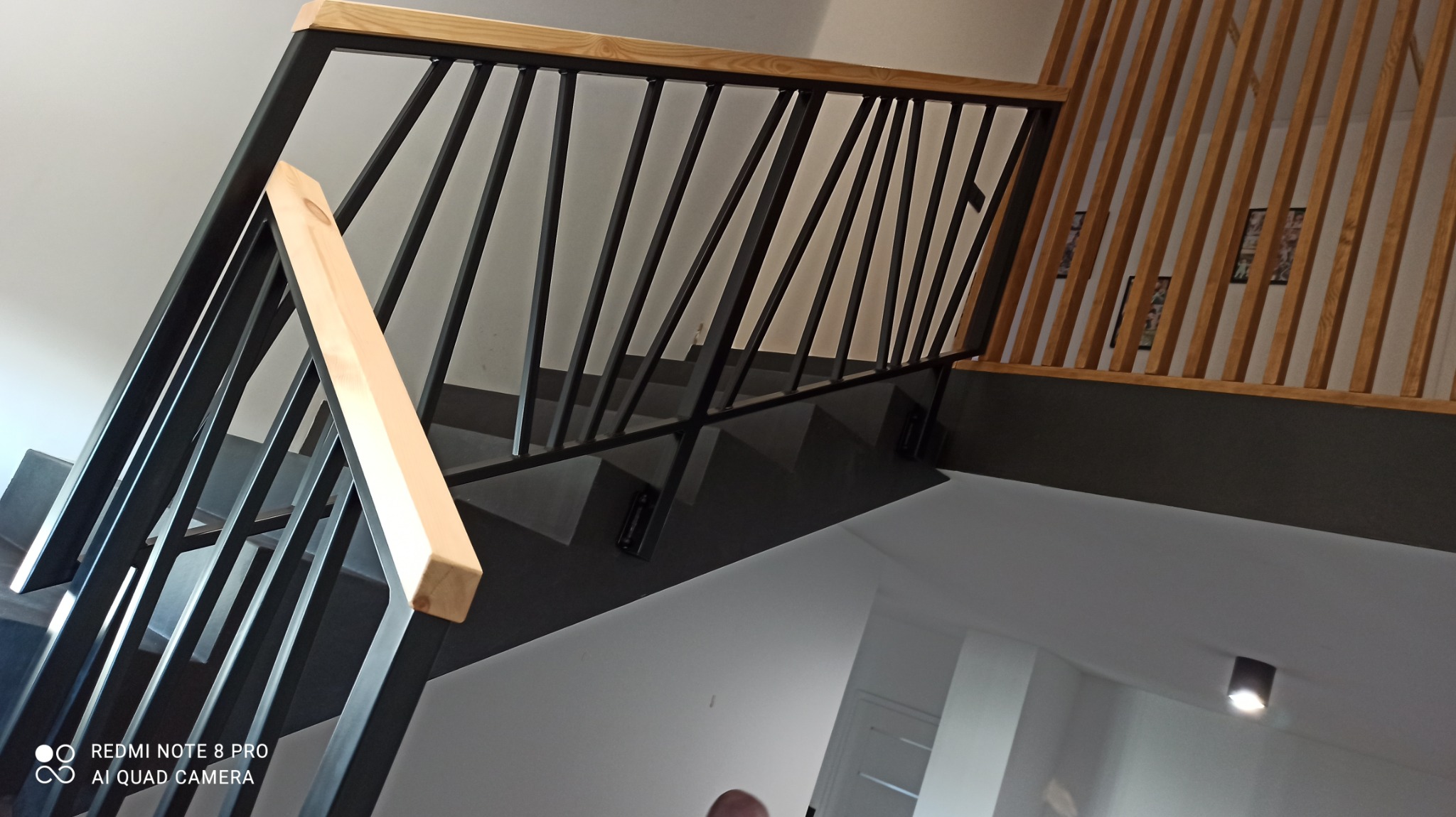 Nowoczesne schody z czarnymi metalowymi elementami i jasnym drewnianym wykończeniem, widok z dołu, minimalistyczny design.