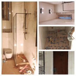 Yakiv Shevchenko - Wnętrze łazienki w trakcie prac wykończeniowych: kabina prysznicowa ze szklaną ścianką, biała armatura, płytki imitujące marmur, narzędzia glazurnicze na podłodze.