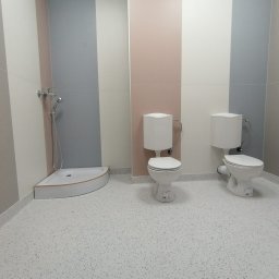 BUILD PROJECT SPÓŁKA Z OGRANICZONĄ ODPOWIEDZIALNOŚCIĄ - Jasna łazienka z dwoma toaletami i narożnym brodzikiem, ściany w pionowe pasy beżu, szarości i różu, podłoga w jasne plamki.