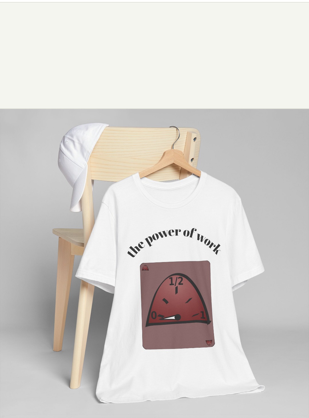 Biała koszulka z napisem 'the power of work' i grafiką na drewnianym wieszaku, zawieszona na jasnym krześle z białą czapką z tyłu. Proste tło.