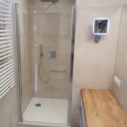 RAD-BUD Radosław Czubasiewicz - Nowoczesna łazienka z kabiną prysznicową typu walk-in, beżowymi płytkami, grzejnikiem drabinkowym i podświetlanym lustrem z odbiciem osoby robiącej zdjęcie.