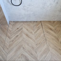 RAD-BUD Radosław Czubasiewicz - Wykończona łazienka z podłogą w jodełkę z drewnopodobnych płytek, odpływ liniowy i podwieszana toaleta z deską wolnoopadającą.