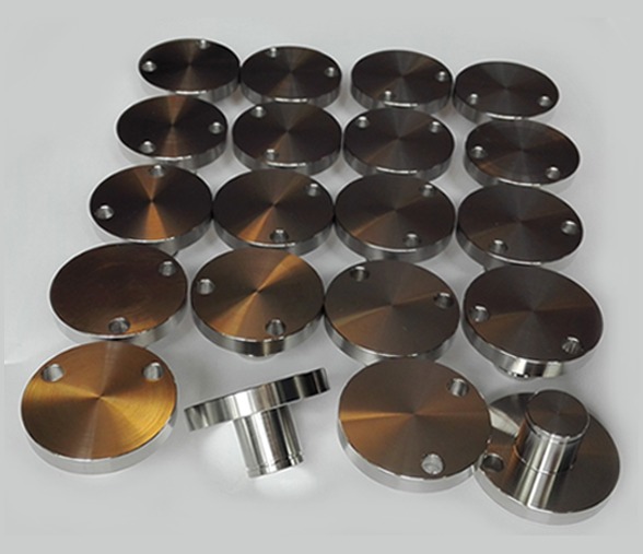 Seria metalowych, okrągłych elementów z trzema otworami, niektóre z dodatkowymi elementami cylindrycznymi, leżących na jasnym tle.