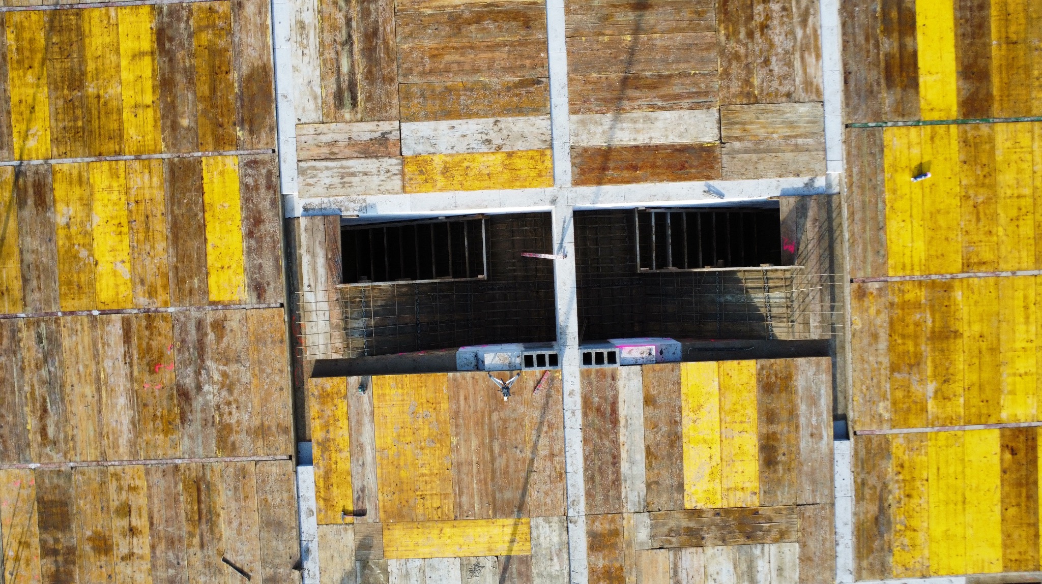 Widok z góry na szalunek fundamentów z otworami okiennymi, widoczne zbrojenie i betonowe bloczki.