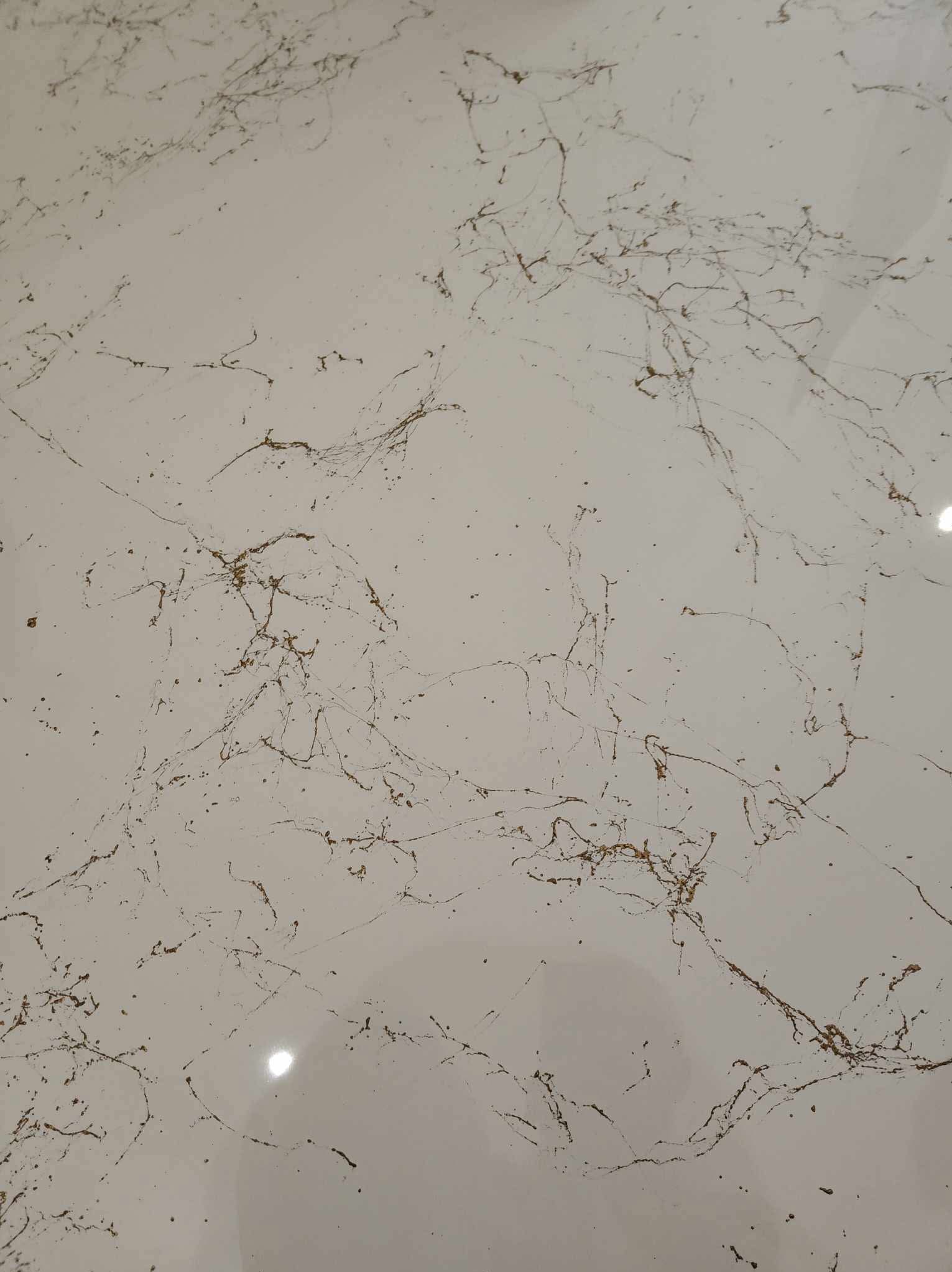 Jasna posadzka z żywicy epoksydowej z brązowymi żyłkami imitującymi marmur, widoczne delikatne refleksy światła.