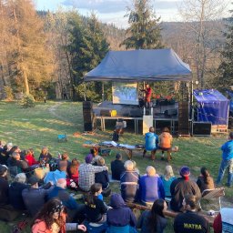 Extreme Sound - Plenerowa impreza integracyjna z występem na scenie i publicznością siedzącą na ławkach w otoczeniu drzew.