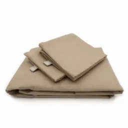 Złożony komplet pościeli bawełnianej w odcieniu beżu, z widocznymi metkami tkanymi, sfotografowany na białym tle.