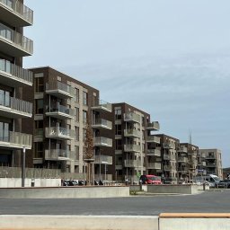 NEUVARTSTAHL SPÓŁKA Z OGRANICZONĄ ODPOWIEDZIALNOŚCIĄ - Nowoczesne budynki mieszkalne z balkonami z szarymi balustradami, widok z dołu na tle pochmurnego nieba.