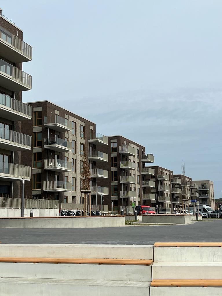 Nowoczesne budynki mieszkalne z balkonami z szarymi balustradami, widok z dołu na tle pochmurnego nieba.