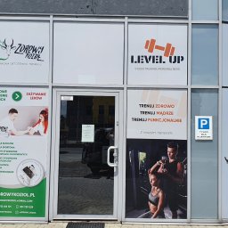 SD Projekt Marcin Sanduła - Fasada budynku z witrynami reklamującymi poradnię dietoterapii i studio treningu personalnego, z widocznymi logotypami, informacjami o usługach i sylwetkami ćwiczących.