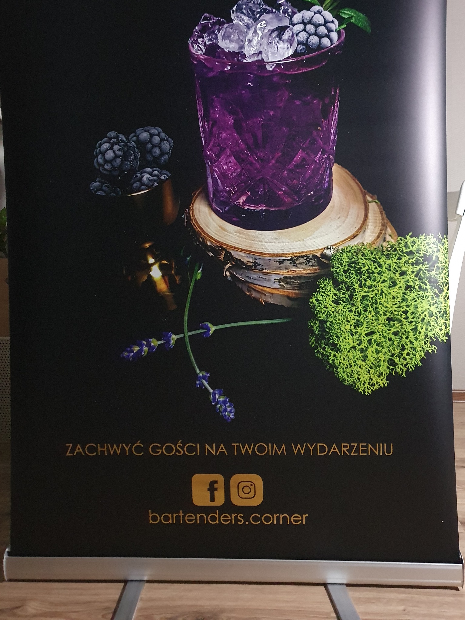 Roll-up reklamowy z drinkiem jeżynowym, lodem i dekoracjami z mchu i lawendy, promujący usługi barmańskie na wydarzenia.