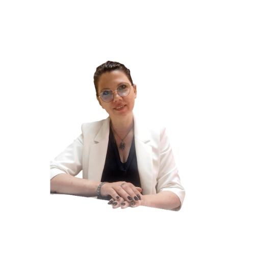 Portret uśmiechniętej kobiety w okularach i białej marynarce, z dłońmi splecionymi na stole, na białym tle.