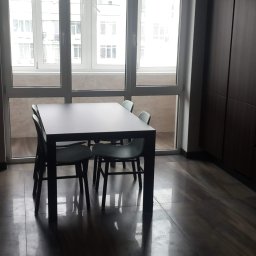 Dmytro Marynchenko - Nowoczesna jadalnia z ciemnymi meblami, płytkami podłogowymi imitującymi drewno i dużym oknem balkonowym w jasnych ramach.