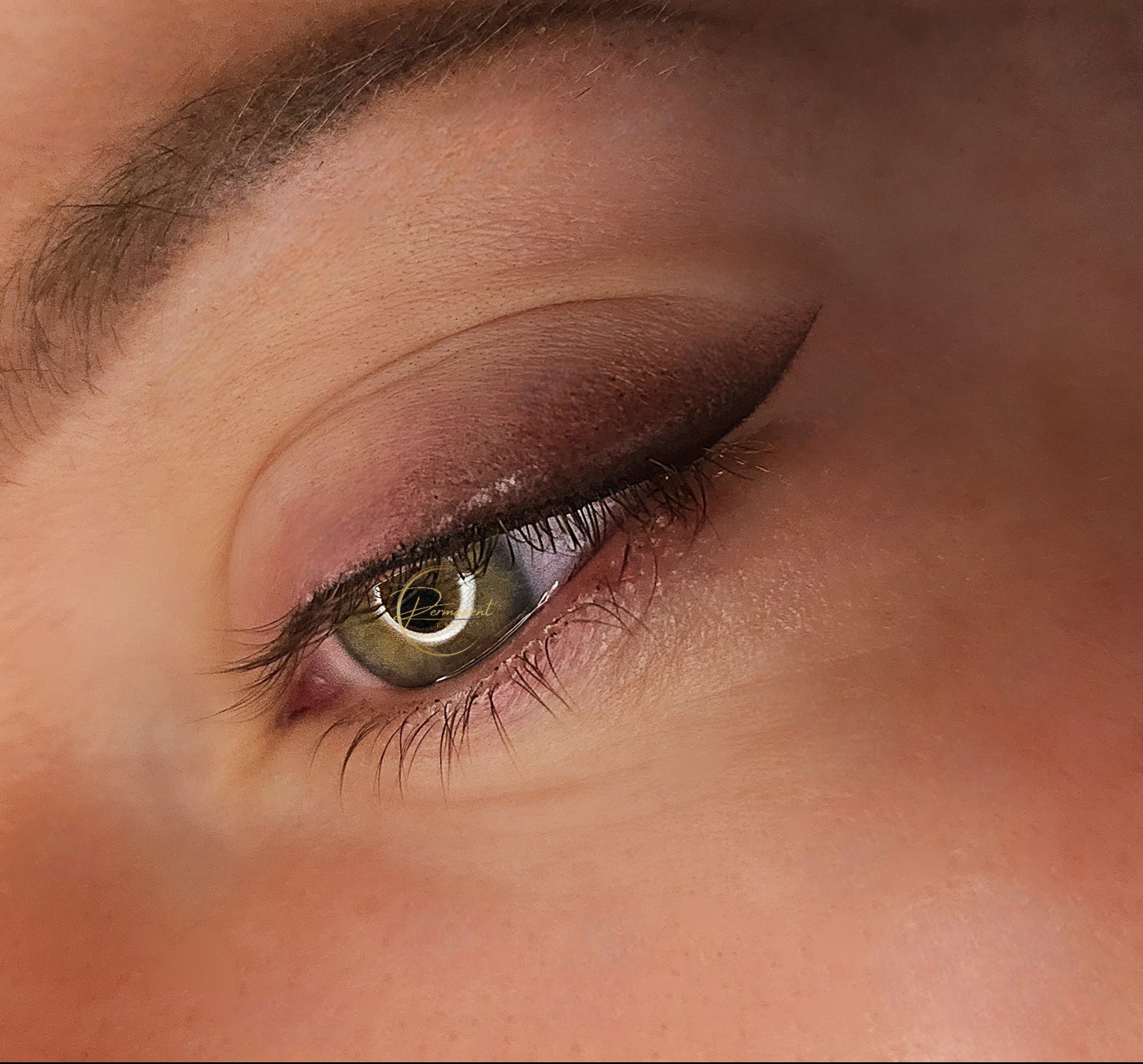 Zamknięte oko z makijażem permanentnym: kreska cieniowana na powiece, widoczne rzęsy i delikatny cień w odcieniach brązu.