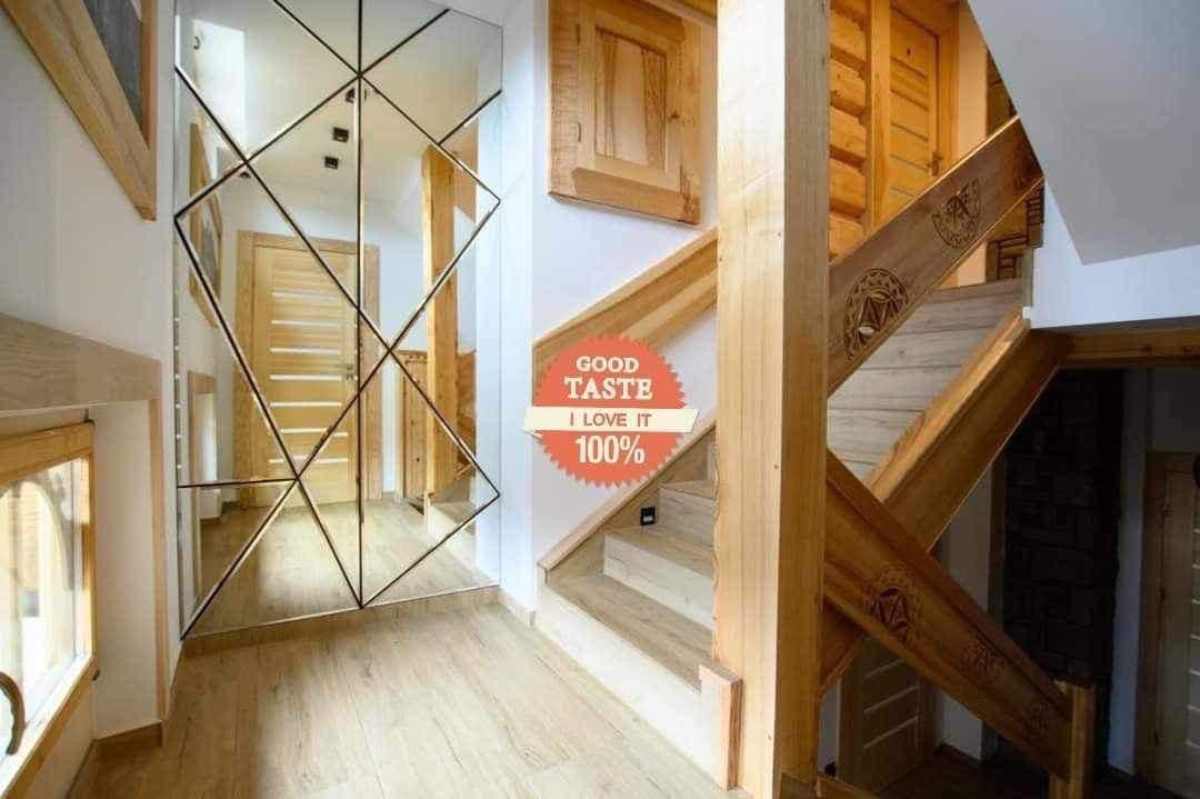 Nowoczesne lustro z geometrycznym wzorem i drewniane schody z rzeźbieniami w jasnym wnętrzu domu w Poroninie.