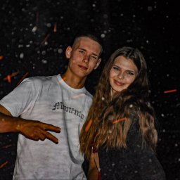 Fotograf SzeVsky - Młoda para pozuje na tle ciemnego nieba z efektem bokeh, mężczyzna w białej koszulce z napisem 'Memento' pokazuje znak pokoju.