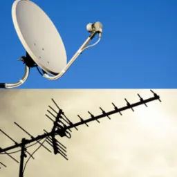 Antena satelitarna i antena naziemna skierowane w niebo, widoczne z dołu.