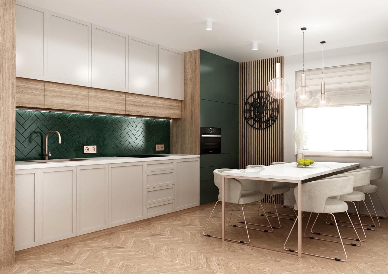 Nowoczesna kuchnia z białymi szafkami, drewnianymi akcentami, zielonymi płytkami ułożonymi w jodełkę i stołem jadalnym z krzesłami w tle.