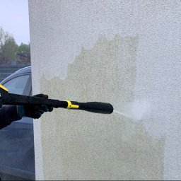 LFant Robert Mirowski - Czyszczenie elewacji budynku myjką ciśnieniową Kärcher, widoczne różnice w kolorze przed i po czyszczeniu, fragment samochodu w tle.