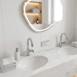 ProStyle - Nowoczesna łazienka z marmurowym blatem, dwoma umywalkami i podświetlanym lustrem o nieregularnym kształcie. W tle wnęka z półkami i ręcznikami.