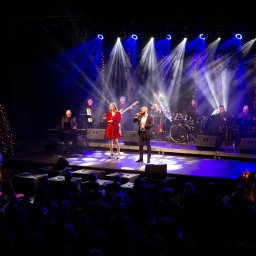 Wave Beats Karol Nadolski - Duet wokalny na scenie z pełnym zespołem muzycznym, oświetlony reflektorami, widok z publicznością w tle.