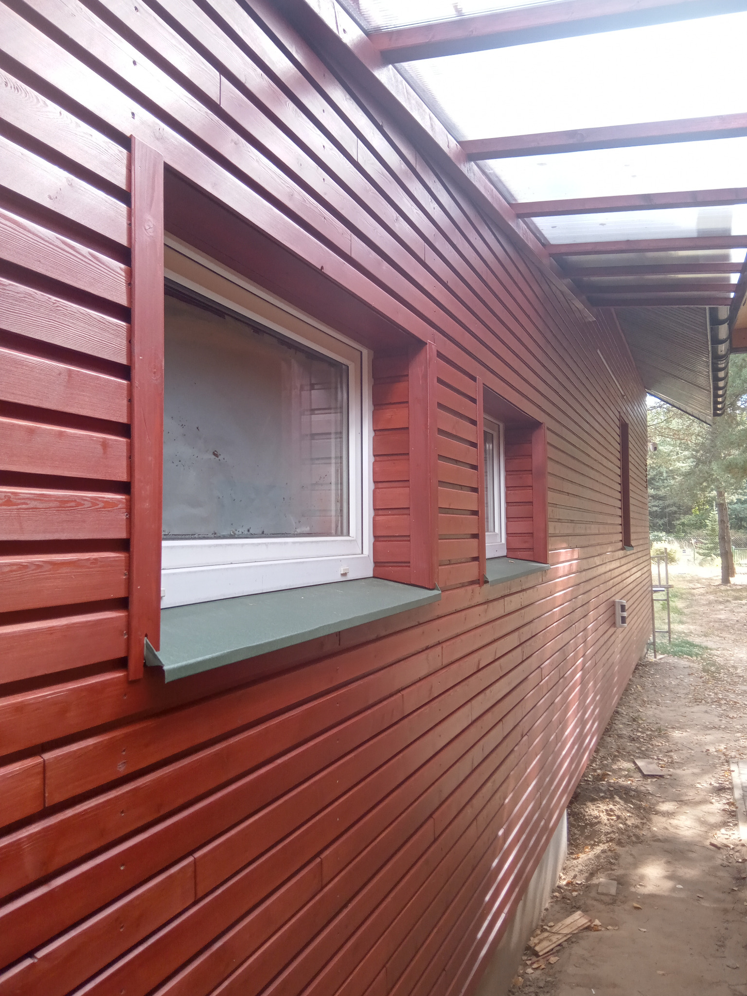 elewacja z ociepleniem - modrzew syberyjski, małe zadaszenie z poliwęglanu pomiędzy budynkami.