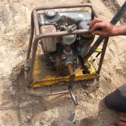 kajetankastynbud - Operator obsługuje starą, żółtą zagęszczarkę gruntu podczas prac przygotowawczych pod fundamenty.