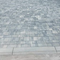 Pmbud - Ułożona szara kostka brukowa na podjeździe, widok z góry, obrzeża z szarego betonu.