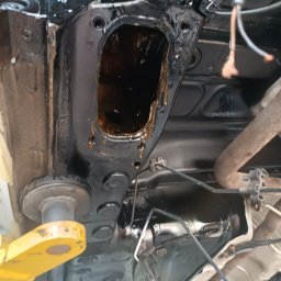 BREMS - Podwozie samochodu na podnośniku, widoczne elementy po zabezpieczeniu antykorozyjnym, świecąca czarna powłoka i fragment układu wydechowego.