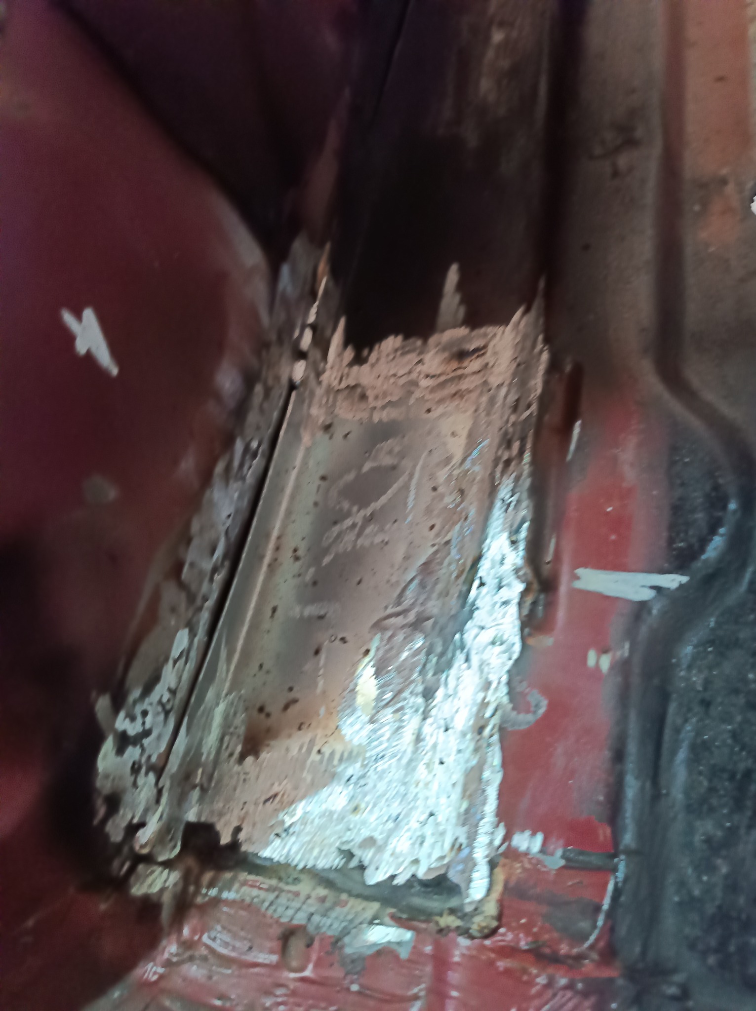 Fragment skorodowanej karoserii samochodu w Serbinowie, przygotowywanej do naprawy blacharskiej z widocznymi śladami korozji i resztkami starej powłoki lakierniczej.